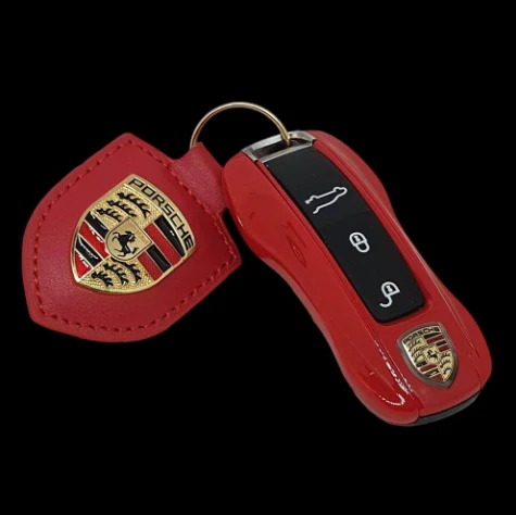 Chave inteligente Porsche vermelha com chaveiro de couro da marca sobre fundo preto